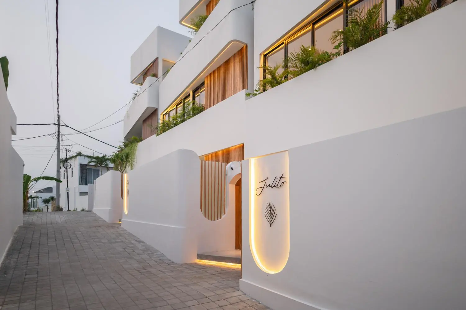 White sculpted facade and entrance at dusk Villa Julito Tumbak Bayu Pererenan Bali