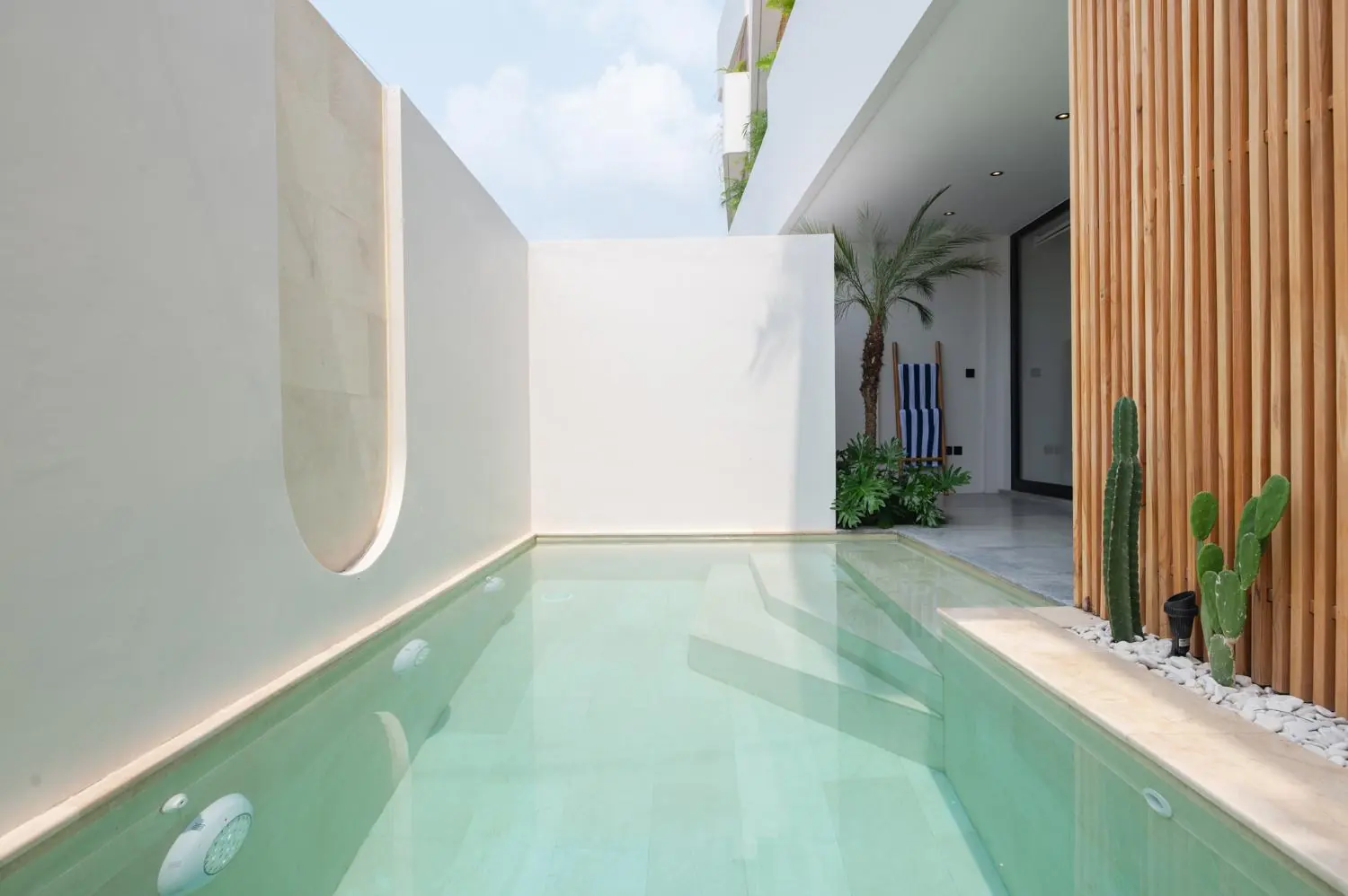 Private pool between white walls and timber slats Villa Julito Tumbak Bayu Pererenan Bali