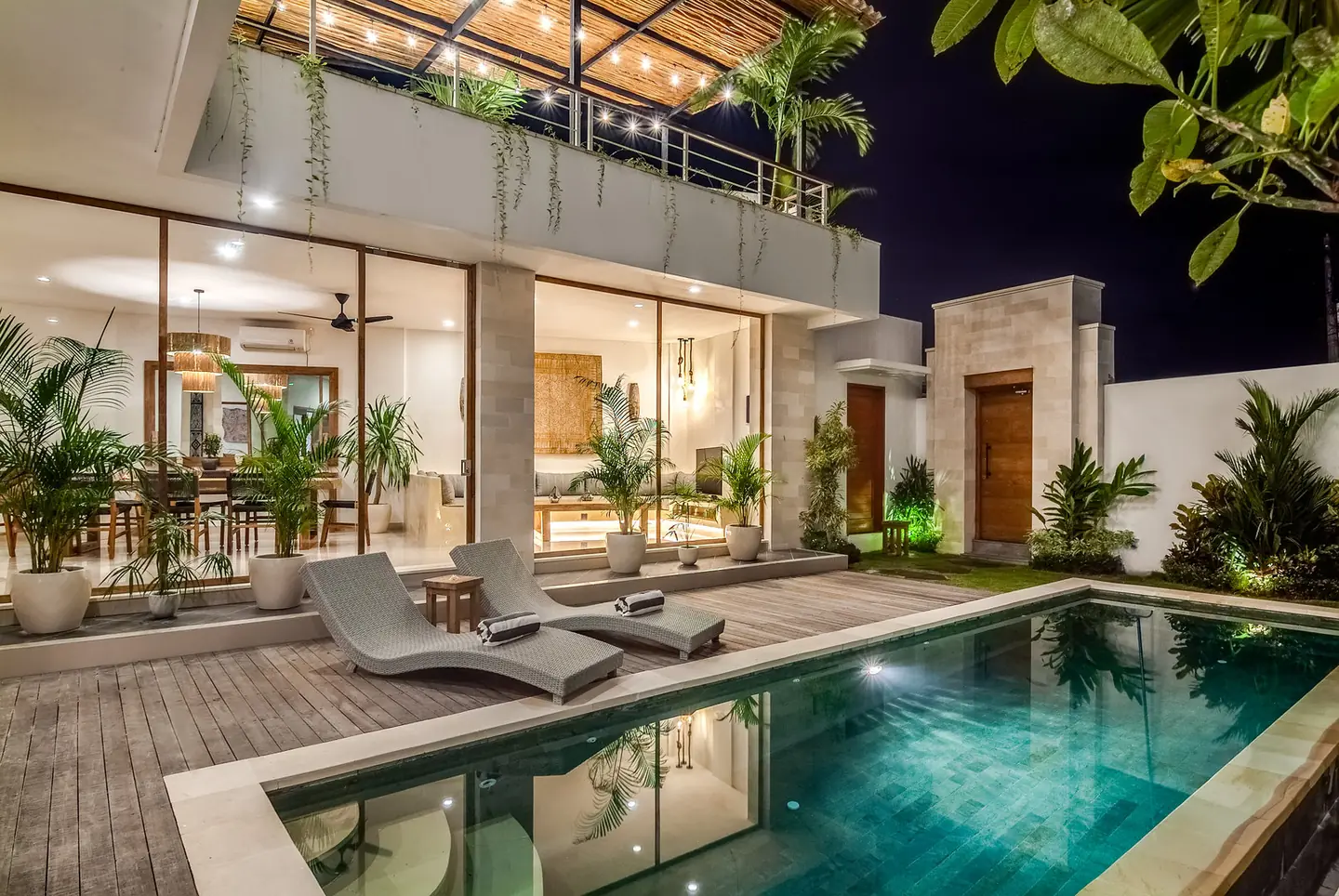Villa Kesari pool deck and glass-fronted living room at night Berawa Canggu Bali
