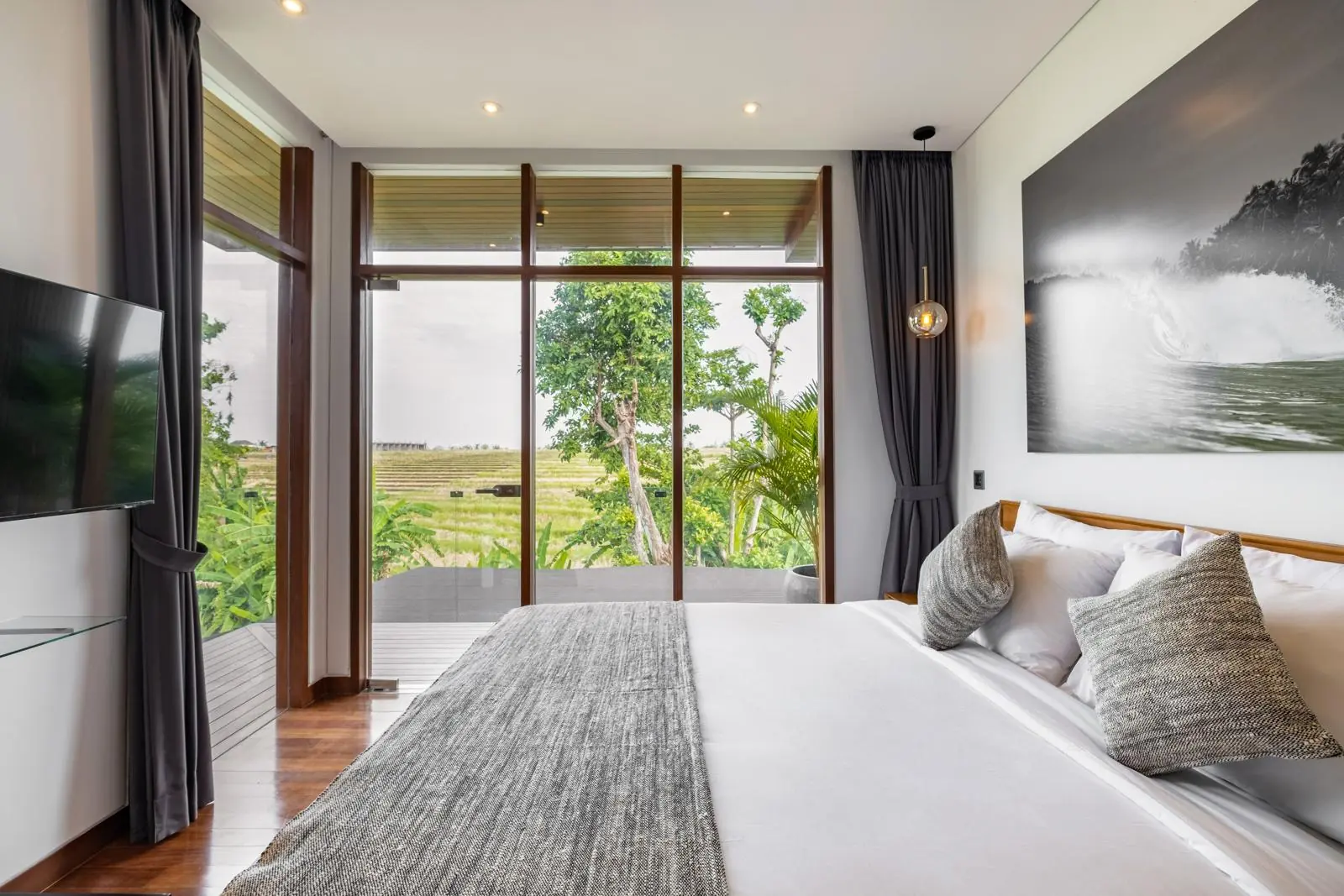 Upper-floor bedroom with balcony and rice field views River Paradise 4BR Pererenan Bali