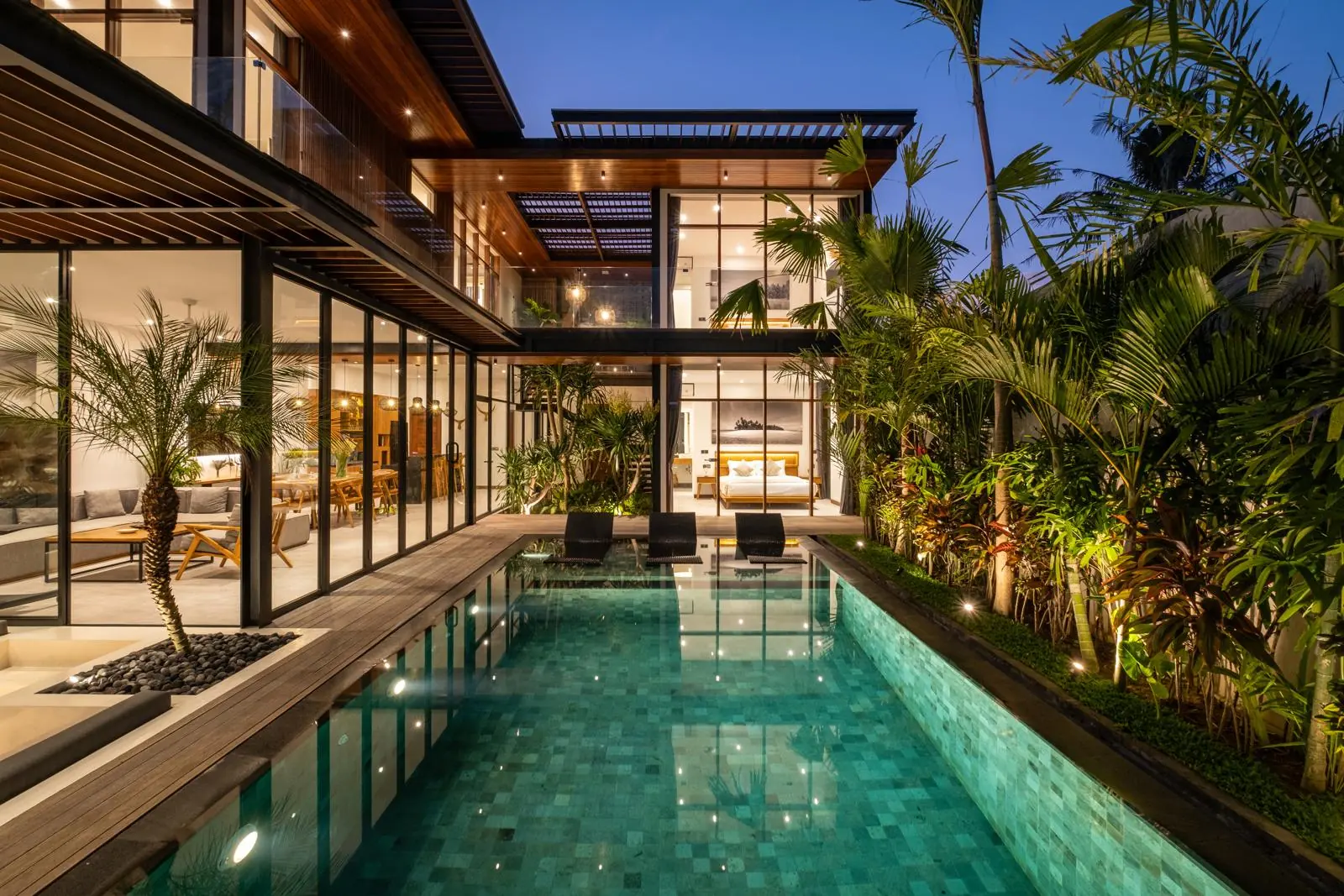 Private pool and two-storey glass villa illuminated at night River Paradise 4BR Pererenan Bali
