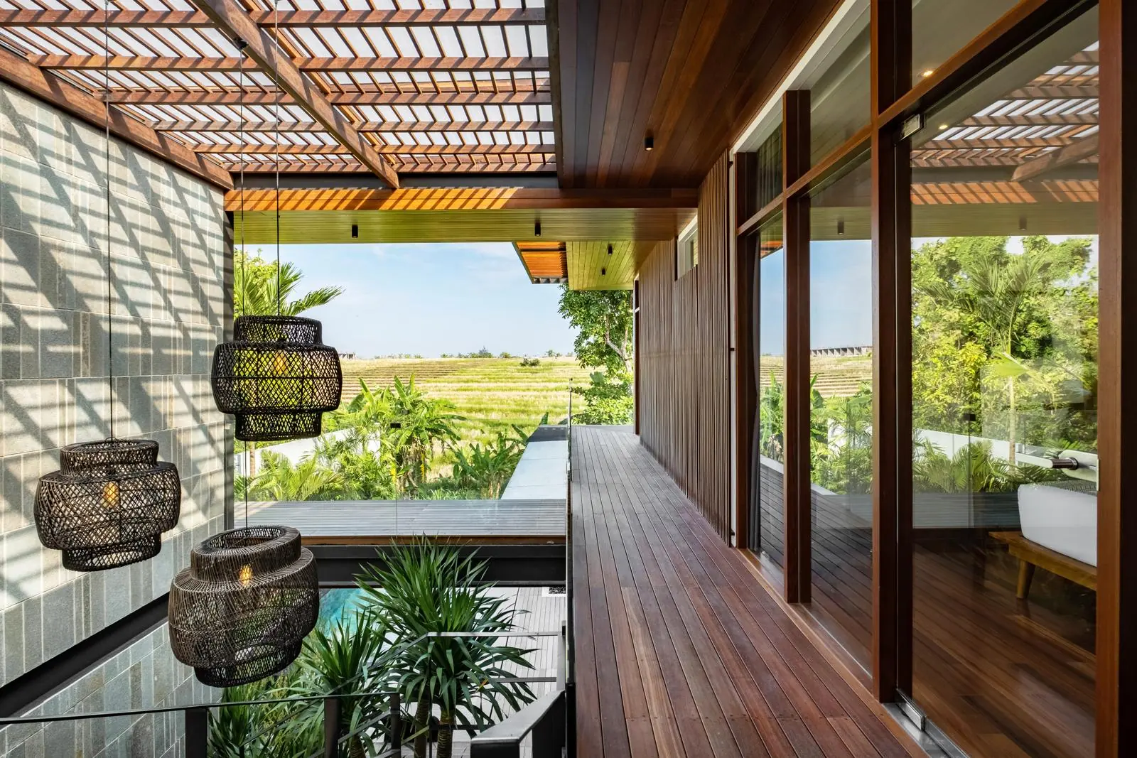 Upper timber walkway with rattan lanterns and rice field views River Paradise 4BR Pererenan Bali